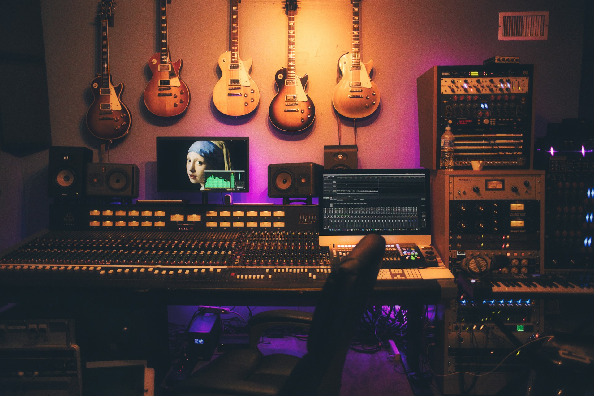 A mixing console with faders and a notepad on the desk